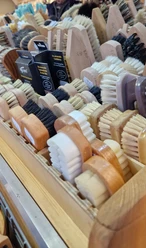 Eine Nahaufnahme handgefertigter Bürsten in verschiedenen Formen und Farben auf einem Marktstand.
