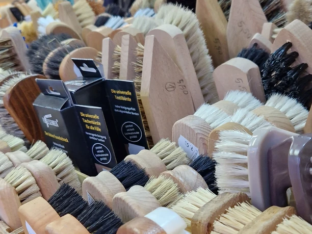 Abendmarkt Vlotho Bürsten Eine Nahaufnahme handgefertigter Bürsten in verschiedenen Formen und Farben auf einem Marktstand.