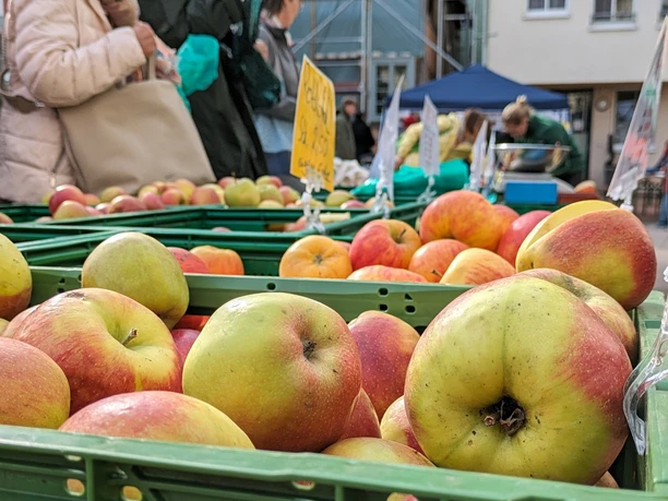 Abendmarkt Vlotho Obst Kisten mit frischen Äpfeln beim Abendmarkt in Vlotho, Besucher im Hintergrund beim Einkaufen.