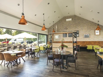 Restaurant im Hotel am Wald in Monheim am Rhein Im Restaurant treffen stilvolle, moderne Inneneinrichtung auf großzügige Fenster und Holzelemente.