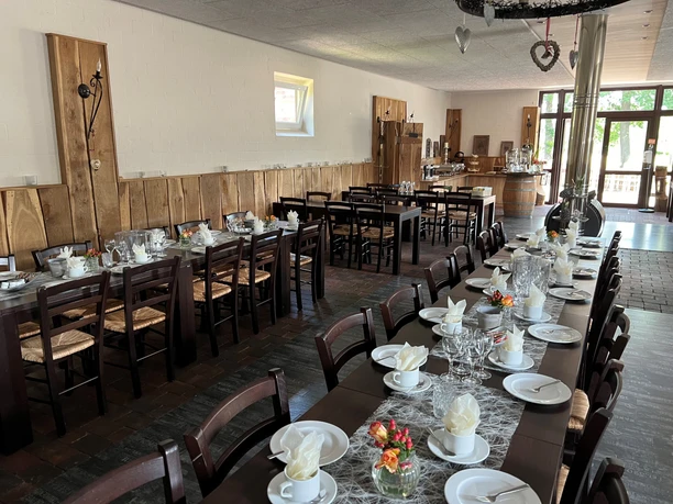 Café Weserscheune Ein geräumiger, einladender Gastraum mit gedeckten Tischen, geschmückten Wänden und hellem Tageslicht.