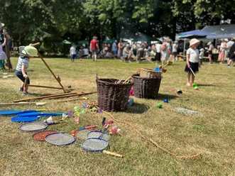 Kinder- und Parkfest vor dem LVR-Industriemuseum in Ratingen Kinder spielen auf einer Wiese mit bunten Spielsachen und Körben, umgeben von Menschen und Bäumen.