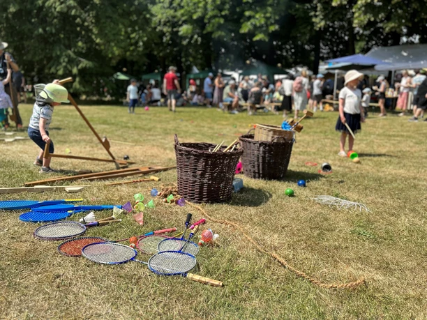 Kinder- und Parkfest vor dem LVR-Industriemuseum in Ratingen Kinder spielen auf einer Wiese mit bunten Spielsachen und Körben, umgeben von Menschen und Bäumen.