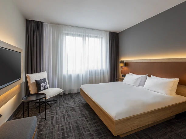 Hotelzimmer im Four Points Flex by Sheraton Ratingen Düsseldorf Airport Modernes Hotelzimmer in Ratingen mit Doppelbett, Flachbildfernseher und großem Fenster für viel Licht.
