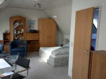 Appartment im Haus Panorama in Ratingen Die Dachgeschosswohnung in Ratingen bietet ein gemütliches Schlafzimmer mit Sitzbereich und Möbeln.
