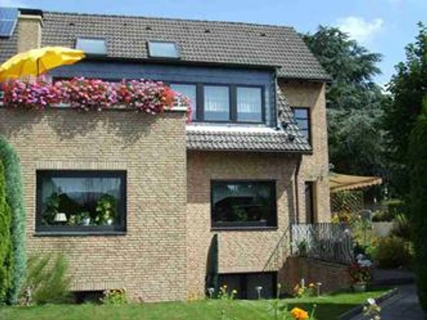 Haus Panorama in Ratingen Modernes zweistöckiges Einfamilienhaus in Ratingen mit Klinkerfassade, bepflanztem Balkon und Garten.