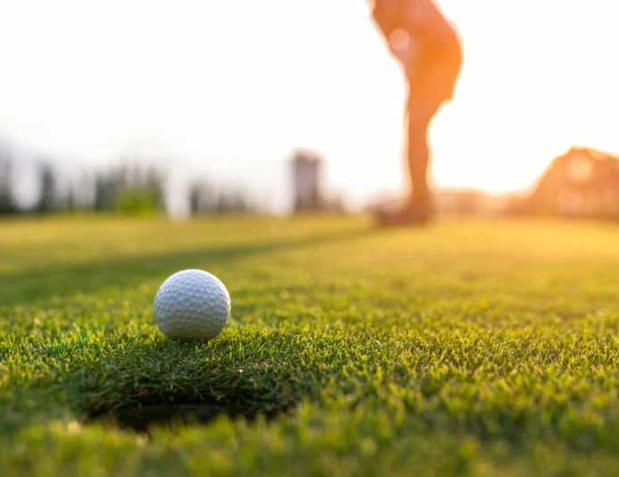Golfer asian woman putting golf ball on the green golf on sun set evening time, select focus. Healthy and Lifestyle Concept.