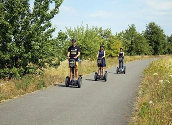 segway-leipziger-neuseenland-grabschützer-see-foto-andreas-schmidt-1-675x491.jpg Drei Personen fahren auf einem Weg durch eine grüne Landschaft mit Segways.