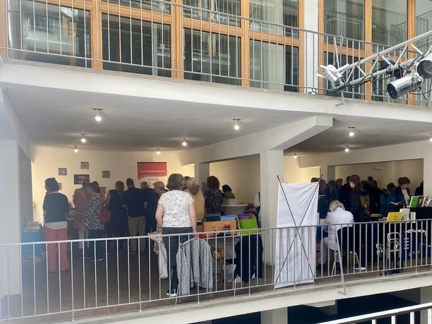 Kölner Bücherfest Menschen stöbern auf einem Bücherfest; Stände mit Büchern, Leuchtleisten an der Decke.