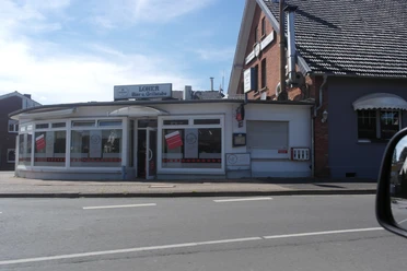 SAM_2019.JPG Auf dem Bild ist die Außenansicht der Loher Grillstube zu sehen. Die Fassade ist weiß und schlicht.