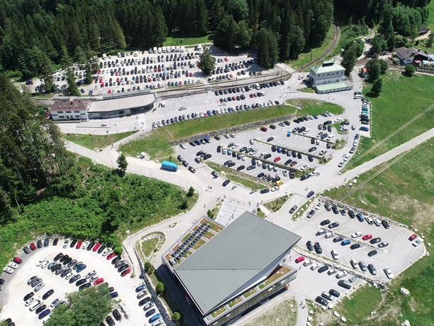 Parkplatz Seilbahn Zugspitze Luftaufnahme eines großen Parkplatzes in Waldnähe mit vielen Autos und umgebendem Grün.