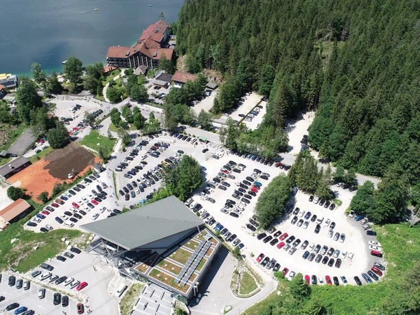 Parkplatz Eibsee Luftaufnahme des Parkplatzes am Eibsee, umgeben von Bäumen und nah am See.
