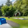 Minigolfanlage in Reichshof-Eckenhagen Minigolfplatz mit blauer Hindernisspirale, umgeben von grünen Bäumen und Wiese, unter blauem Himmel.