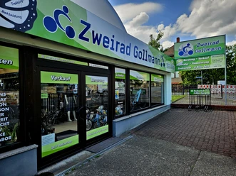 Zweirad Gollmann entree Fietsenwinkel "Zweirad Gollmann" met groene en blauwe uithangborden, etalage met fietsen en accessoires, zonnige sfeer.