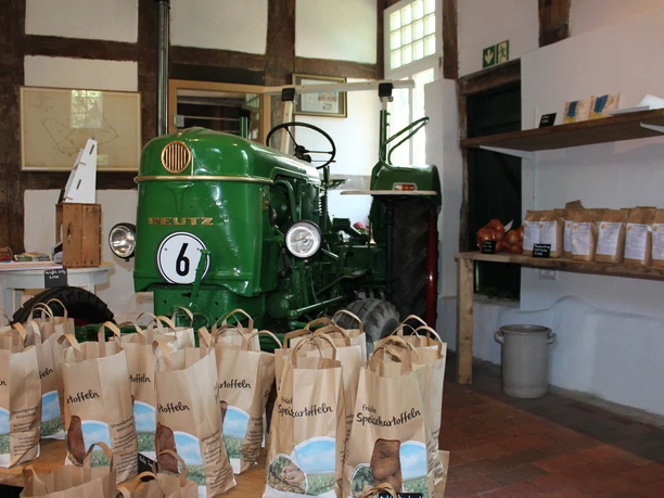Schroeter & Wielage, Bawinkel - Innenansicht Hofladen ©Emsland Tourismus GmbH (2).JPG Grüner Deutz-Traktor im Hofladen mit Säcken frischer Speisekartoffeln und Regalen mit Hofprodukten