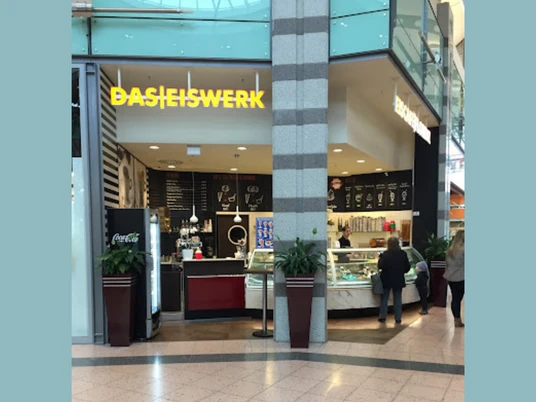 DasEiswerk2.png Das Bild zeigt das Eiswerk im Werre-Park. Rechts erkennt man die Theke an der zwei Personen eine Bestellung abgeben. Links sieht man einen Kühlschrank und weitere typische Utensilien, die zu einer Eisdiele gehören.