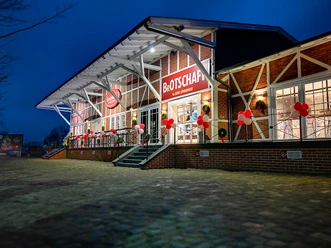 Karlchens.jpg Das Bild zeigt die Fassade aus rotem Klinker mit einer einladenden Treppe, die zur Eingangstür führt. Am Geländer der Treppe sind rote und weiße Ballons befestigt, die eine festliche und freundliche Atmosphäre schaffen.