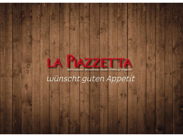 piazetta1.jpg Zu sehen ist das Logo des Imbiss. Der Hintergrund besteht aus einer Holzwand, während der Schriftzug in Rot gestaltet worden ist, der "La Piazetta wünscht guten Appetit" lautet.