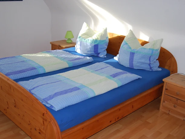 Doppelzimmer in der Ferienwohnung Lang in Velbert Zwei Betten mit blauen und grünen Bettdecken befinden sich in einem hellen Zimmer mit Holzmöbeln.