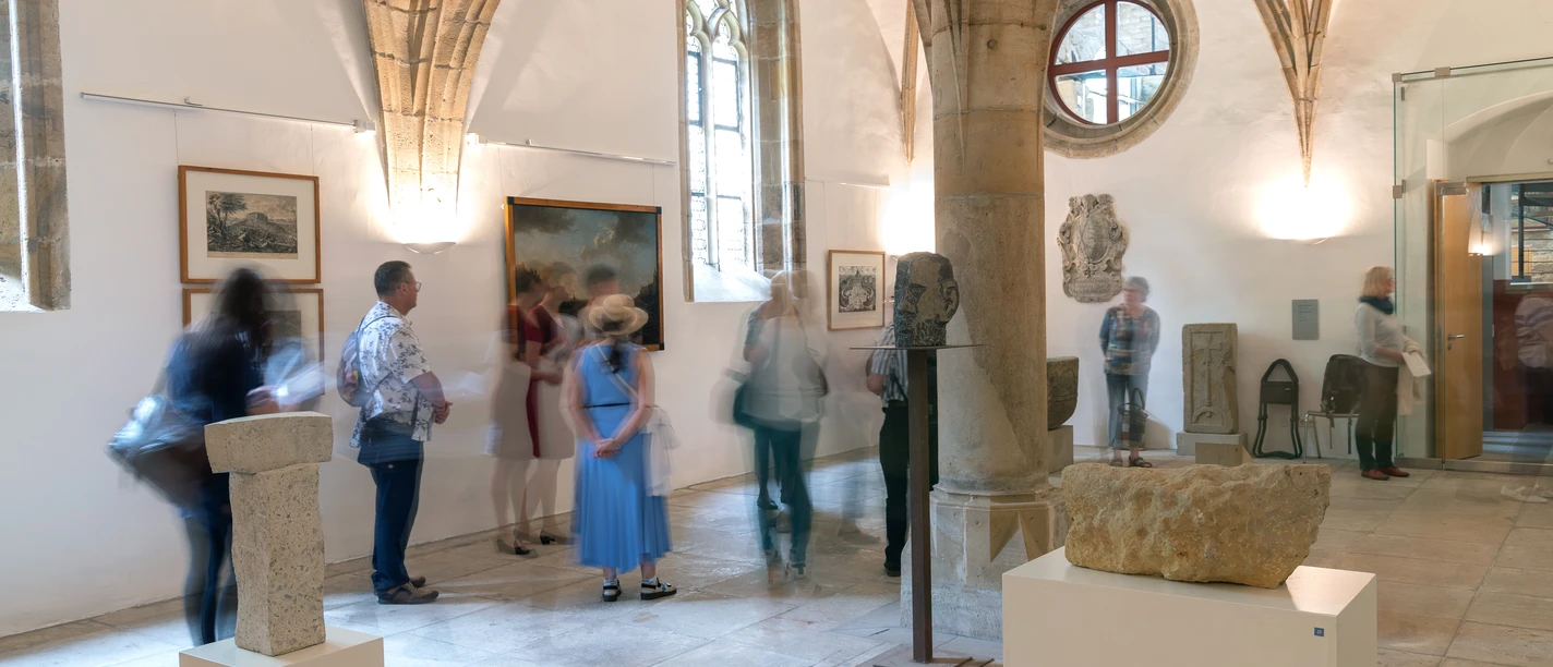 pirna-canalettos-blick-10-c-frank-hoeppner.jpg Eine Gruppe von Menschen betrachtet Kunstwerke in einer lichtdurchfluteten Galerie.