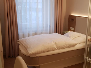Einzelzimmer im Stüttgens Hotel in Velbert Ein Einzelzimmer mit einem Bett, TV, Fenster, Schreibtisch, Stuhl und einem modernem Badezimmer.