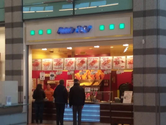 pp.jpg Zu sehen ist der Potato Point im Werre-Park, vor dem sich eine lange Schlange gebildet hat. Die Einrichtung des Imbisses ist in auffälligen Farben wie Gelb und Rot gestaltet. An der Wand hängen zahlreiche Tafeln, die verschiedene Gerichte beschreiben und die Auswahl noch verlockender machen.