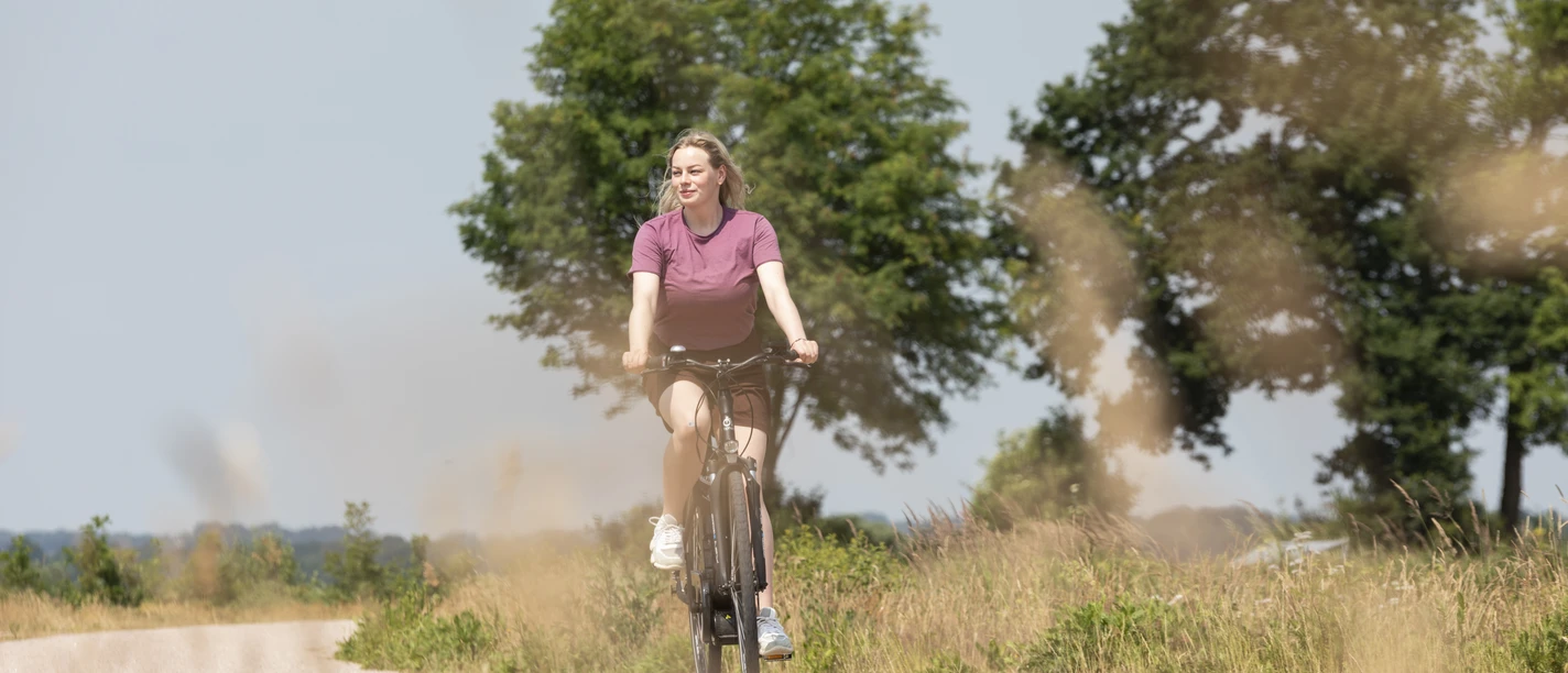 Mit dem Rad durch das Teufelsmoor Eine Radfahrerin fährt im Sommer durch die Hammeniederung und genießt die Sonne.