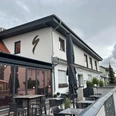 Außenansicht des Restaurants Zur Schanze Büren mit Terrasse, Tischen und durch Schirme bedeckt.