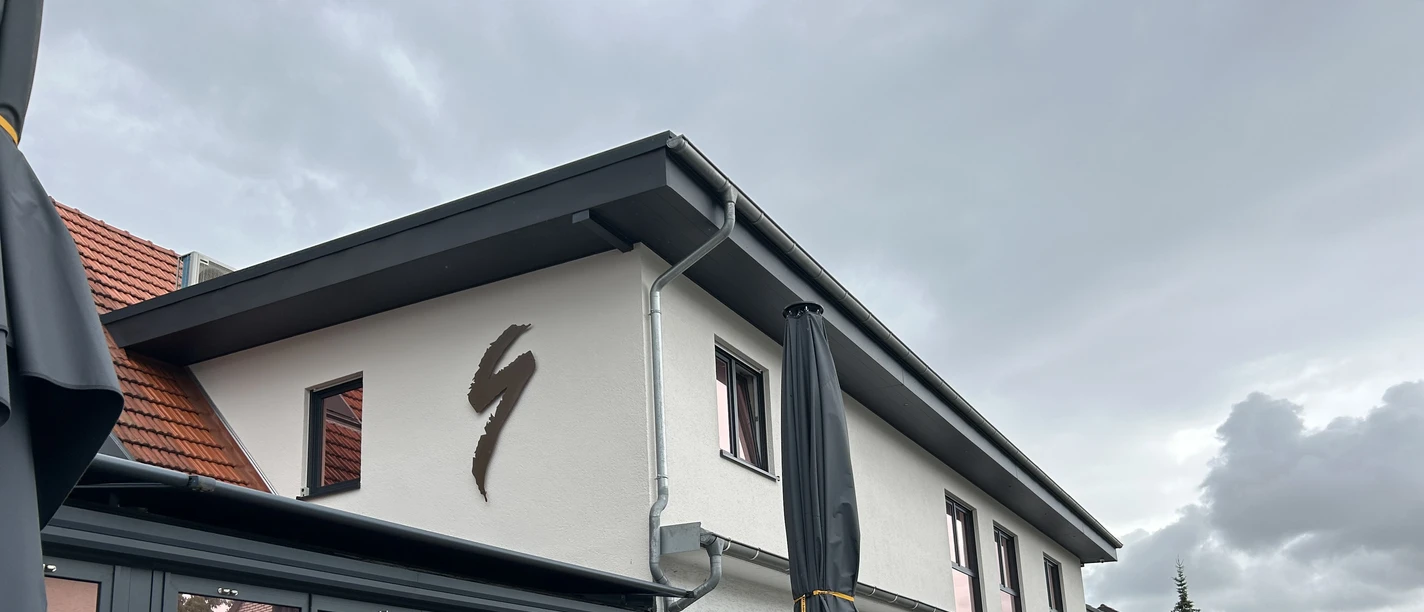 Außenansicht des Restaurants Zur Schanze Büren mit Terrasse, Tischen und durch Schirme bedeckt.