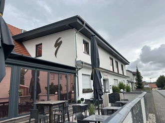 Restaurant Zur Schanze | Büren Außenansicht des Restaurants Zur Schanze Büren mit Terrasse, Tischen und durch Schirme bedeckt.