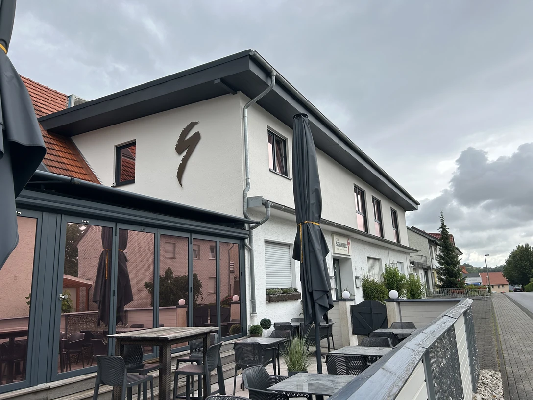 Restaurant Zur Schanze Büren Außenansicht des Restaurants Zur Schanze Büren mit Terrasse, Tischen und durch Schirme bedeckt.