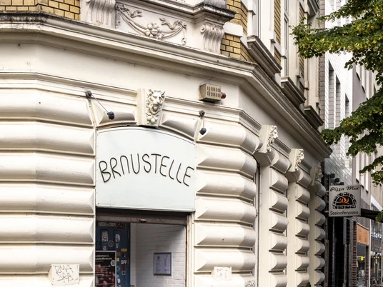 Braustelle Historische Fassade mit gelben Backsteinen. Der Eingang zur Braustelle führt durch eine blaue Tür.