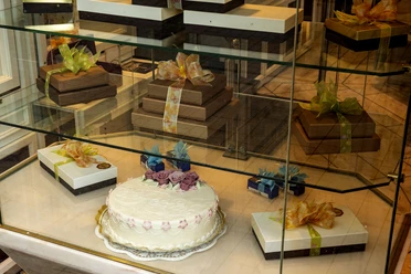 Cafe Reichard Vitrine mit schön verzierten Präsenten und üppiger Torte mit Marzipandekor.