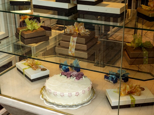 Cafe Reichard Vitrine mit schön verzierten Präsenten und üppiger Torte mit Marzipandekor.