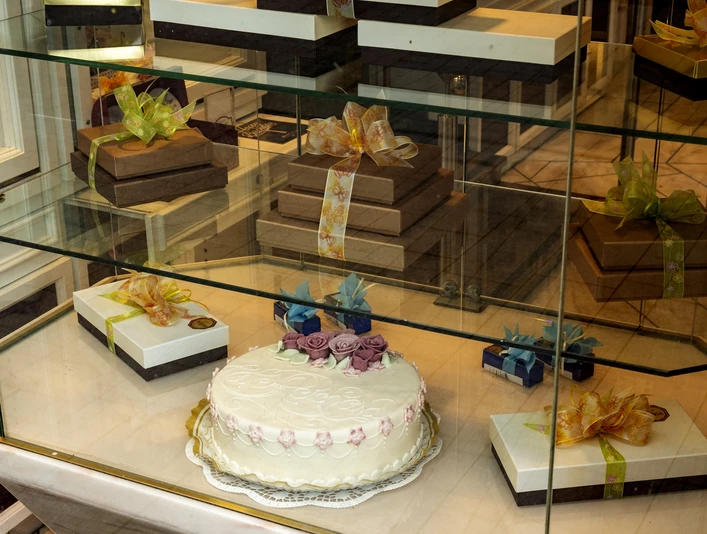 Cafe Reichard Vitrine mit schön verzierten Präsenten und üppiger Torte mit Marzipandekor. Display case with beautifully decorated presents and a lavish cake with marzipan decoration.