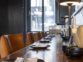 Daikan Izakaya Bar Eingedeckte Theke mit dunklen Tellern und Essstäbchen.Set counter with dark plates and chopsticks.