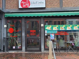 Asia Wok Vlotho ist ein Schnellimbiss mit asiatischer Küche. Vor dem Eingang stehen Pflanzen.