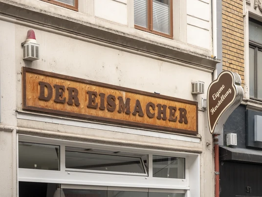 Der Eismacher Einladender Eingang einer modernen Eisdiele mit stilvoller Holzbeschilderung in urbanem Umfeld.Inviting entrance of a modern ice cream parlor with stylish wooden signage in an urban setting.