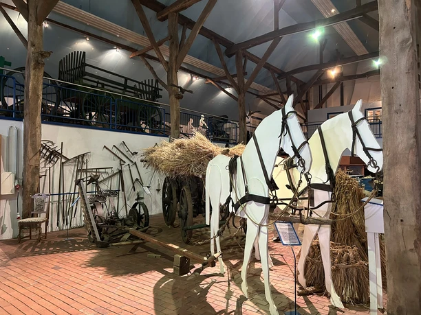 Landwirtschaftsmuseum Rhede (Ems) Ausstellungsraum mit historischen landwirtschaftlichen Geräten und Holzpferden vor einem Heuwagen
