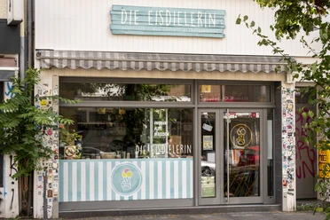 Die Eisdielerin Fröhliche beige Fassade mit hell blauem Schild aus Holzbrettern .