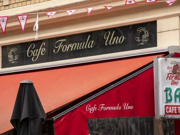 Formula Uno A black sign with the inscription Formula Uno hangs on the façade. A garland of pennants flutters in the wind.