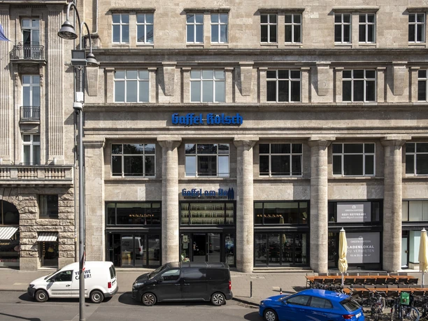 Gaffel am Dom Totale von der Hausfassade. Parkende Autos stehen vor dem Gebäude.