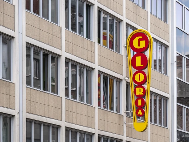 Gloria Das Bild zeigt das mehrstöckige, moderne Gebäude des Gloria-Theaters in einer Innenstadtlage.