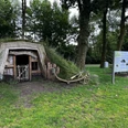 Plaggenhütte Nordloh mit Infotafel.jpg Eine traditionelle Plaggenhütte, neben einem Baum, mit Infotafel und Bank im Grünen.