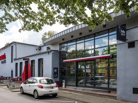 Herbrand's Außenansicht auf das Herbrands mit großer Glasfront und Fahrradständer davor.Exterior view of the Herbrands with large glass front and bicycle racks in front of it.