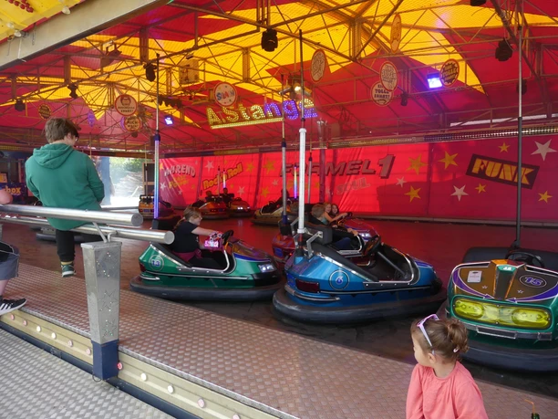 Festplatz_Auto-Scooter.JPG Bunte Autoscooter mit fahrenden Kindern auf einem beleuchteten Festplatz.