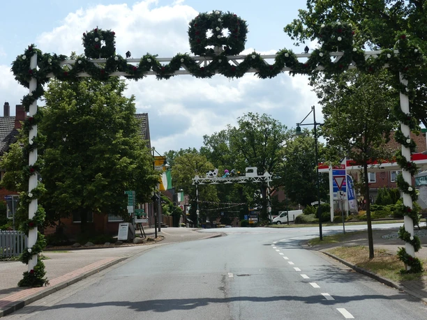 Ehrenpforte.JPG Ehrenpforte mit grünen Girlanden und Kränzen über einer Straße zum Schützenfest in Bispingen.