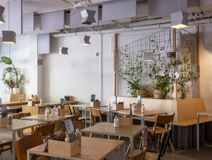 Kaffeesaurus Blick in das modern eingerichtete Café mit hellen Holzmöbeln und Pflanzen.View of the modern café with light wood furniture and plants.