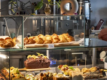 Kaffeesaurus Vitrine im Café mit Kuchen, Gebäck und belegten Broten.Display case in a café with cakes, pastries, and sandwiches.