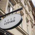 Keep Loving Ein ovales Schild mit der Aufschrift "Keep Loving" hängt an einem historischen Gebäude in der Stadt.An oval sign with the words "Keep Loving" hangs on a historic building in the city.